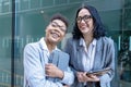 businesswomen wearing office suits with digital tablet, talking and smiling. Joyful business partners concept