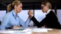 Two businesswomen doing arm wrestling in office, concept of rivalry at work