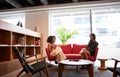 Two Businesswomen Having Socially Distanced Meeting Sitting On Office Sofa