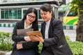 Two businesswomen looking at tablet while holding paper file holder