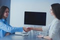 Two businesswomen sitting at a desk shaking hands Royalty Free Stock Photo
