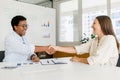 Two businesswomen sitting at the desk and shaking hands each other in sign of cooperation Royalty Free Stock Photo