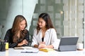 Two businesswomen sitting at office desk and talking about project startup ideas. Royalty Free Stock Photo