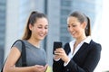 Two businesswomen talking about smart phone