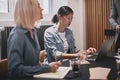 Two businesswomen working during a boardroom meeting with collea