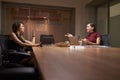 Two businesswomen working late in an office talking