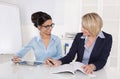 Two businesswomen working together at desk at office. Royalty Free Stock Photo