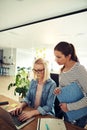 Two businesswomen working together in an office using a laptop Royalty Free Stock Photo