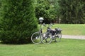 Two bycicles parked near bushes in park.