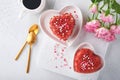 Two cakes Red velvet in shape of hearts on white plate, rose flowers and cup of coffeeon on pink romantic background. Dessert idea Royalty Free Stock Photo