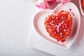 Two cakes Red velvet in shape of hearts on white plate, rose flowers and cup of coffeeon on pink romantic background. Dessert idea