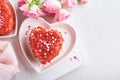 Two cakes Red velvet in shape of hearts on white plate, rose flowers and cup of coffeeon on pink romantic background. Dessert idea