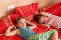 Two calm bored young girls, school age children laying on the bed at home together, relaxing, holidays, vacations, exhausted kids