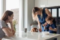 Two calm and disappointed women and little sad boy, refusing food sit with dog in kitchen. Picky eater, different habits Royalty Free Stock Photo