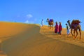 Two cameleers and women with camels walking on sand dunes of thar desert , Jaisalmer, Rajasthan, India Royalty Free Stock Photo