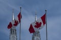 Two Canadian flags waving against blue sky in front of Catholic Church towers. Royalty Free Stock Photo