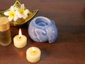 Two candles, a gold pattern dish, and aromatherapy bottle