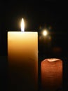 Two candles lighting the darkness on dark background with a reflective backdrop Royalty Free Stock Photo