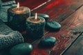 two candles near stones and a towel on red wooden background Royalty Free Stock Photo