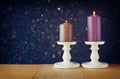 Two candlesticks with burning candles over wooden table and vintage glitter background Royalty Free Stock Photo