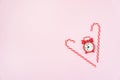 Two Candy Cane and Red Clock on Pink Background Christmas Backround or Concet Holidays Morning Flat Lay Hoizontal