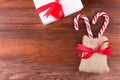 two candy canes in sack bag with white gift box red ribbon bow on dark wooden board Royalty Free Stock Photo