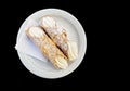 Two canoli with butter cream laid out on a plate over black back