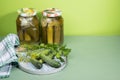 Two cans of pickles and gherkins. Pickled pickles on a round wooden chopping Board with herbs.