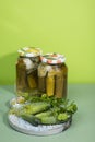 Two cans of pickles and gherkins. Pickled pickles on a round wooden chopping Board with herbs.