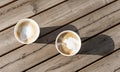 Two cappuccino in beige paper cups on wooden striped table outside, drinking coffee, meeting friends top view Royalty Free Stock Photo