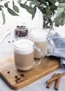 Two cappuccino or latte with milk foam in glasses on a light blue background with coffee beans, cinnamon and eucalyptus branch Royalty Free Stock Photo