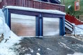 Two car garage of home with shiny metal doors under the deck with wooden railing