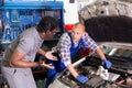 Two car mechanic diagnosing auto engine problem in service Royalty Free Stock Photo