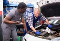 Two car mechanic diagnosing auto engine problem in service Royalty Free Stock Photo