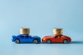 Two car models with coin stacks are head to head against blue background. Concepts of car insurance, auto crash, road accident.