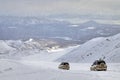 Two car SUV drives through snow-covered mountain valley with deep snow after snowstorm.