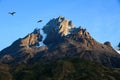 Two Caracaras silhouetted against the blue sky over a rocky granite mountain, Torres del Paine National PArk