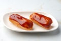 Two caramel eclairs on a white plate