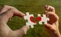 Two cardboard puzzles with a painted red heart are held in the hands Royalty Free Stock Photo