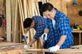 Two carpenters are working in a wood factory. The carpenter is sawing and cutting wood Royalty Free Stock Photo