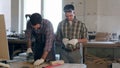 Two carpenters working with wooden planck and electric planer in workshop. Royalty Free Stock Photo