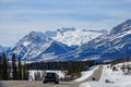 Two cars drive down the empty road leading towards the snowy Canadian Rockies. Royalty Free Stock Photo