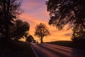 Two cars on rural road with automobile headlight on at sunset