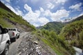 Two cars on a serpentine road in the mountains, mountain peaks in the snow and green hills background Royalty Free Stock Photo