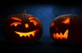 Two carved faces of pumpkins glowing on Halloween on blue background Royalty Free Stock Photo