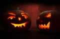 Two carved faces of pumpkins glowing on Halloween on red background Royalty Free Stock Photo