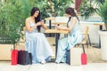 Two casual young women looks to smartphone after shopping at outdoors cafe. Royalty Free Stock Photo