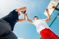 Two Caucasian basketball player fighting for ball possession at the basketball court on a sunny day