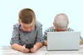 Two Caucasian boys ,brothers on a white isolated background. one plays in the phone,the other in the laptop. modern children and Royalty Free Stock Photo