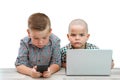 Two Caucasian boys ,brothers on a white isolated background. one plays in the phone,the other in the laptop. modern children and Royalty Free Stock Photo